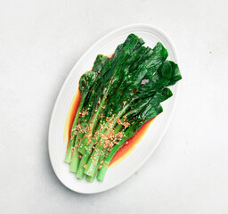 Stir-frying Chinese Broccoli, Gai Lan or Chinese Kale on a white plate, top view