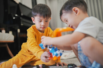 Two young boys play creatively with colorful toy blocks on the carpet, fostering imagination and teamwork in a cozy home setting.