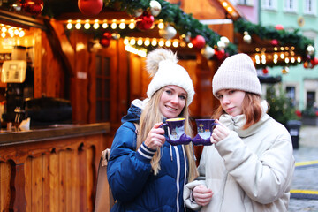 Two girls drink hot tea or coffee on Christmas market in Wroclaw, Poland 