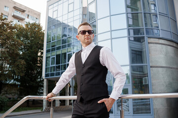 Stylish businessman posing confidently against a modern architectural backdrop