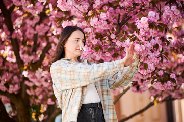 Fototapeta premium Woman allergic suffering from seasonal allergy and runny nose disease at spring. Young woman with paper tissues inserted into nose - symbolic gesture of inability to breathe due to nasal congestion.