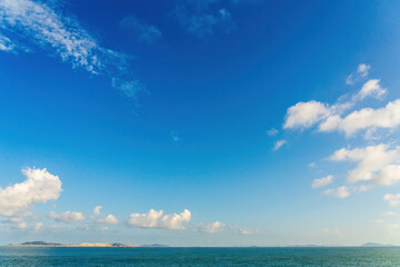 Fototapeta premium Tranquil Seascape with Vibrant Blue Sky and Soft Clouds