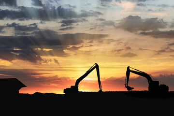 Crawler excavators silhouette are digging the soil in the construction site. on  sunset background