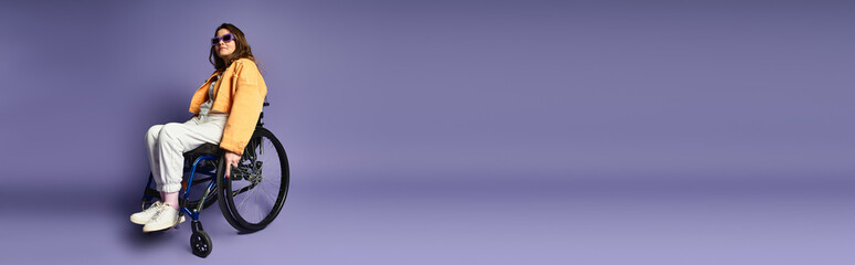 A young woman in a wheelchair poses in a studio with a purple background.