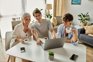 Three family members enjoy a joyful moment together, sharing coffee and smiles in a cozy setting.