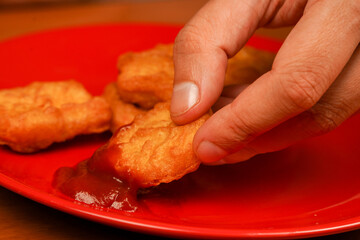 Calories. Obesity. American food. Man eating chicken nuggets. Unhealthy lifestyle. Fast food. Junk food. Chicken nuggets with ketchup. Holding chicken nuggets.