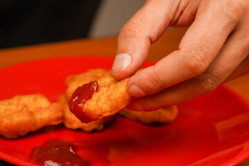 Man eating chicken nuggets. Unhealthy lifestyle. Fast food. Junk food. Chicken nuggets with ketchup. Holding chicken nuggets. Calories. Obesity. American food.