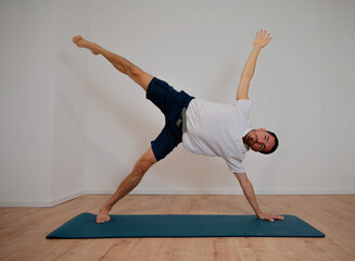 Naklejka premium Caucasian Latino male practicing opening and balancing yoga posture during home session