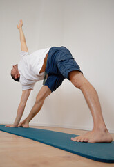 Caucasian Latino male performing the Open Pincer yoga pose in a yoga session at home.