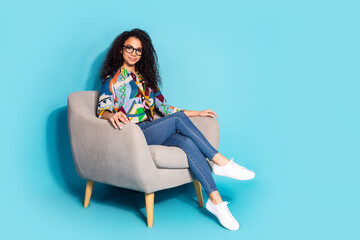 Photo of charming lovely woman wear stylish clothes sit comfortable armchair empty space isolated on blue color background