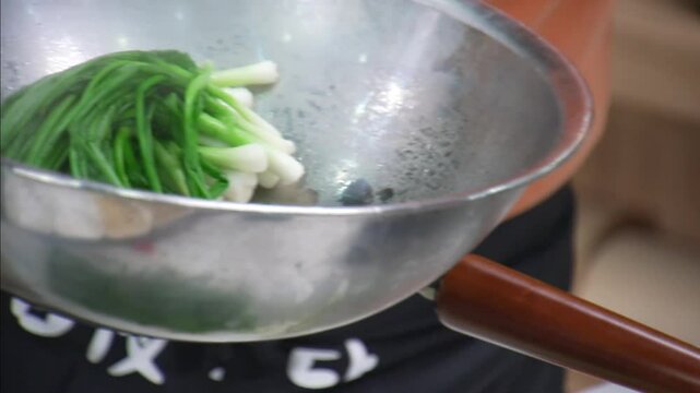 끓는 물에 살짝 데친 파를 건져 금속 그릇에 담는 모습
