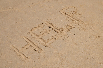 beach sand with the words HELP, concept of lost at sea needing help