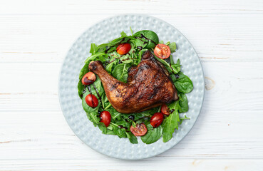Grilled chicken legs with tomatoes and salad . Top view