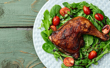 Grilled chicken legs with tomatoes and salad . Top view