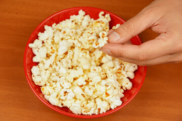 Delicious snack to eat in the cinema. Salted popcorn. Popcorn. Fast food. Junk food. Snack for cinema. Flavored spicy popcorn scattered on table surface. Bowl of tasty popcorn on wooden table.
