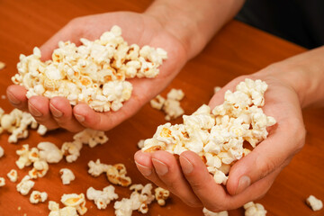 Delicious snack to eat in the cinema. Flavored spicy popcorn in man's hands. Salted popcorn....