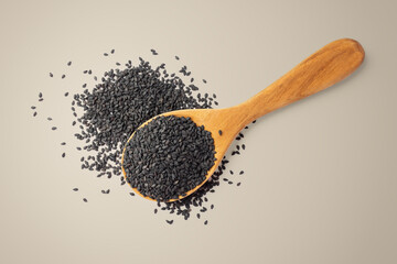 Black sesame seeds in wood spoon on brown background