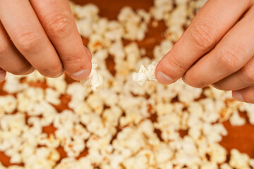 Flavored spicy popcorn in man's hands. Salted popcorn. Popcorn. Fast food. Junk food. Snack for cinema. Popcorn scattered on table surface. Delicious snack to eat in the cinema.