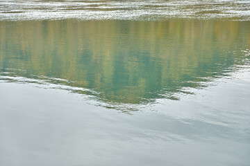 Serene lake reflection of lush green forest and clouded sky in peaceful nature setting.