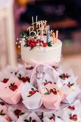 Beautiful birthday cake with cupcakes with colorful birthday candles and raspberries. Holiday cake. 