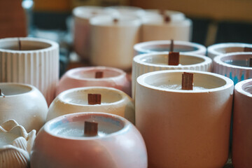 Many soy wax candles together on store or workshop background. Ecological and vegan business. Soy candles poured into recycled bottles and jars.