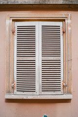 Closed Shutters of a Window on a Plastered Building Wall