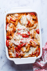 Baked pasta with tomatoes and mozzarella cheese in oven dish.