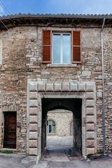 Naklejka premium A charming cobblestone street in medieval Assisi, (Umbria, Italy), featuring ancient stone buildings and vibrant flower pots