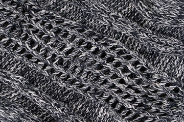 Background of gray knitted dense with white and black threads. Part of knitted sweater.