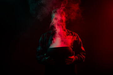 Photo of sorcerer conjurer hold cauldron make conducting ritual halloween night isolated on dark misty mysterious background