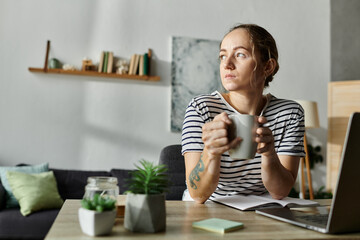 A beautiful woman with vitiligo sips tea while thoughtfully gazing out the window.