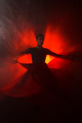 Silhouette of a woman in a red skirt dancing Latin in smoke in neon light. Dance concept. Bachata,...