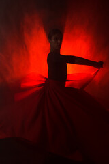 Silhouette of a woman in a red skirt dancing Latin in smoke in neon light. Dance concept. Bachata,...