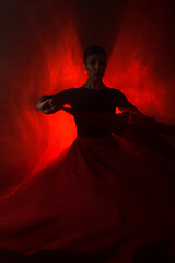 Silhouette of a woman in a red skirt dancing Latin in smoke in neon light. Dance concept. Bachata,...