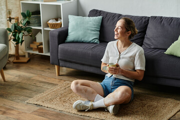 Obraz premium A woman with vitiligo sits happily on the floor, enjoying a warm drink.