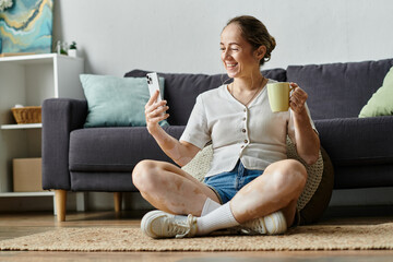 A woman smiles brightly while chatting on her phone, sipping a warm drink.