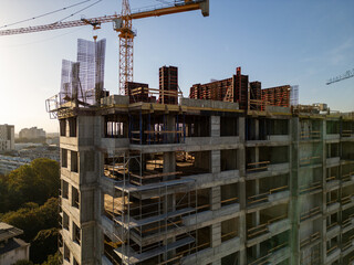 A drone video capturing the construction site of a high-rise building at sunset. The structure's...