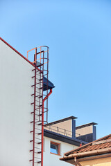 Secure stairs to the roof of the building. Metal. Red. Industrial building vertical shot