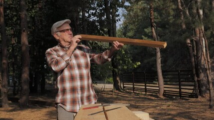 An elderly man showcases traditional woodworking techniques while measuring and crafting with care in a serene forest setting during daylight.