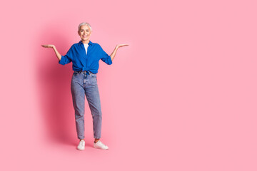 Full length photo of shiny attractive lady dressed blue shirt comparing arms empty space isolated pink color background