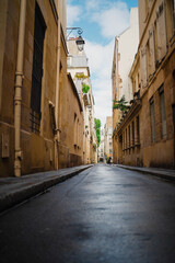 Narrow Alleyway with Wet Concrete Floor and Small Sidwalk Enclosed in Old Building Walls
