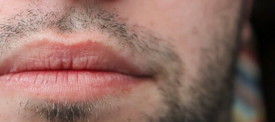 Close-up of male lips with stubble, showcasing natural textures and tones. Ideal for beauty and grooming themes