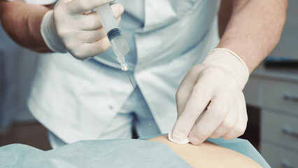Doctor administering injection to patient. Close-up of a doctor carefully administering an injection to a patient's lower back in a clinical setting.