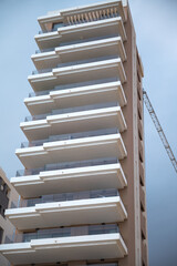 Modern high-rise apartment building with glass balconies and crane