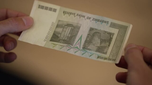 10조 짐바브웨 달러 지폐를 들고 있는 손