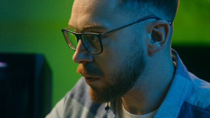 Concentrated Caucasian crypto trader man male late night work touching keys keyboard computer freelancer boy worker looking monitor writing statistics at home stock analyzing results digital banking