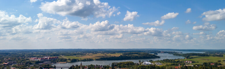 A stunning panoramic view of Mikolajki, showcasing the lush greenery intertwined with shimmering water bodies under a bright blue sky.