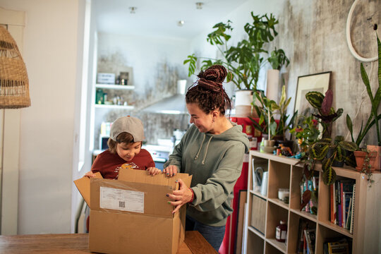 Mother and son unboxing delivery package at home
