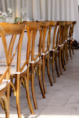 Row of elegant wooden chairs lined up in a bright, sunlit room with white curtains