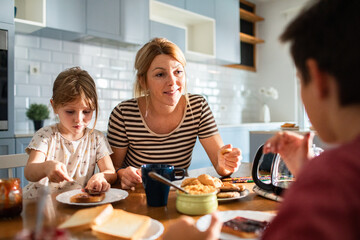 Mother eating breakfast with her kids on kitchen table